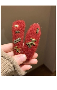 Detail of red wool hair clips with gold dog ornaments and handmade metal engraving