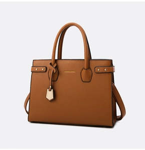 Detail of brown litchi pattern leather handbag with gold logo and elegant shield charm