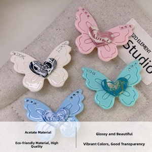 Detail of four acetate butterfly hair clips with rhinestone wings and LOVE heart pattern