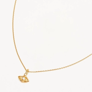 Golden eye pendant necklace with clear zircons on a delicate chain in minimalist style