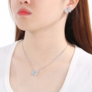 Detailed close-up of a silver butterfly necklace and stud earrings set with sparkling crystals