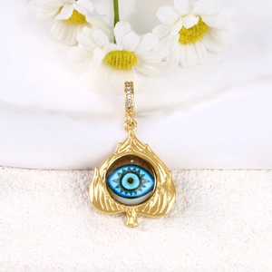 Macro detail of gold plated Evil Eye pendant with blue zircon inlay on white daisies