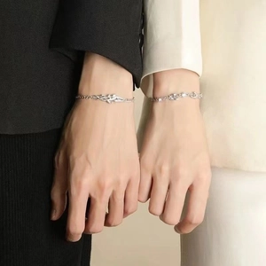 Elegant silver mistletoe couple bracelets with zircons worn on wrists in warm light
