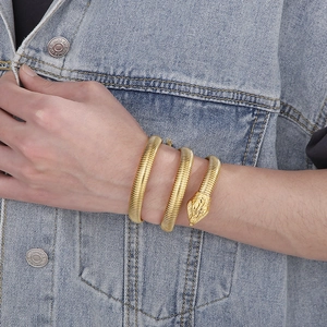 Golden snake-shaped multi-wrap stainless steel bracelet worn on a denim jacket background