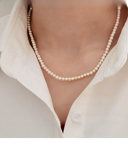 Close-up of elegant natural freshwater pearl necklace worn on a white shirt collar