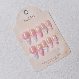 Detail of pink almond press-on nails featuring 3D bows, snowflakes and stripe patterns