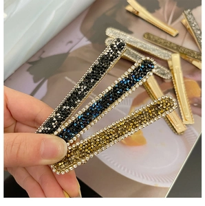 Detailed view of colorful rhinestone hair clips in navy, black, and gold metal finishes