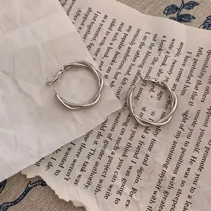 Detailed view of silver twisted hoop earrings on vintage book pages with a minimalist aesthetic