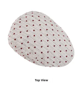 Top view of cream knitted newsboy cap featuring detailed red heart embroidery and fine texture
