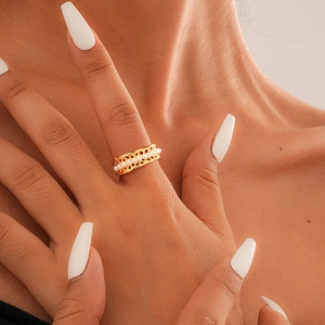 Close-up of gold hollow lace ring with small white pearls on a finger