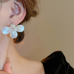 Elegant white mother-of-pearl flower stud earring with central pearl on model ear