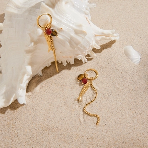 Golden stainless steel fish earrings with tassels and agate beads on beach shell