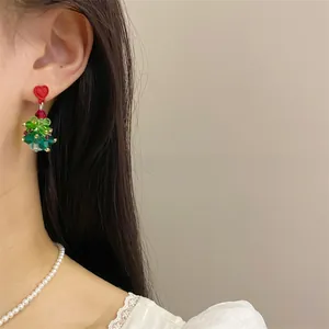 Detail of beaded crystal Christmas tree earrings with red heart stud on female model