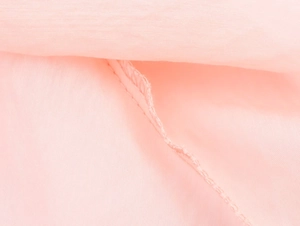 Close-up of pink textile fabric showing stitching details and sheer texture on a midi dress