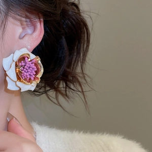 Gros plan détaillé d'une boucle d'oreille fleurie blanche et violette sur un mannequin