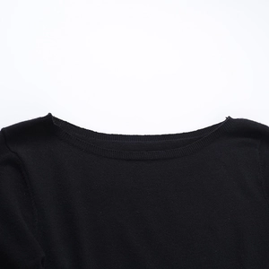 Detalle del tejido de punto negro de alta calidad y el escote ondulado en el vestido