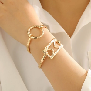 Detail of gold-plated open bangles with hammered texture and geometric hollow shapes