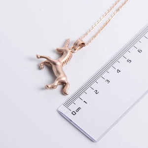 Rose gold unicorn pendant necklace shown with a ruler for size measurement and scale