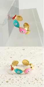 Macro detail of 18k gold plated evil eye ring showing colorful enamel eyes and adjustable band