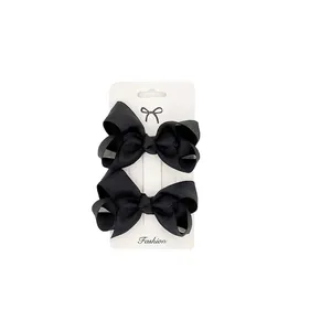 Detail of two black grosgrain ribbon hair bows on a white display card with hooks
