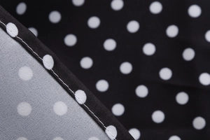 Close-up of black and white polka dot fabric texture with precise stitching detail