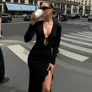 Détail de la robe noire moulante à manches longues avec fente latérale et décolleté à lacets
