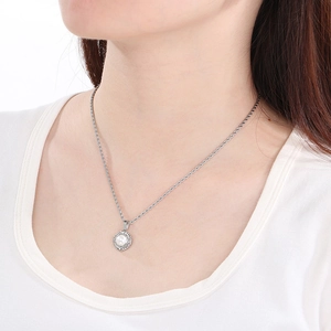 Detail shot of a silver-tone necklace with a pearl pendant and decorative outer ring