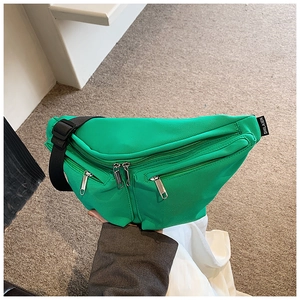 Detail view of bright green nylon crossbody bag showing three silver metal zippers