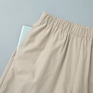 Detail of wide elastic waistband and deep side pocket on beige casual trousers