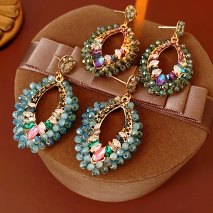 Détails de boucles d'oreilles bohèmes avec cristaux colorés dans un coffret cadeau