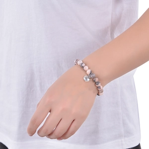 Pink zebra stone beaded bracelet with silver leaf pendant on a female wrist