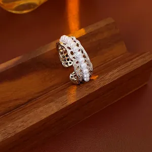 Lace hollowed-out ring with small white pearls on a vintage brown wooden stand