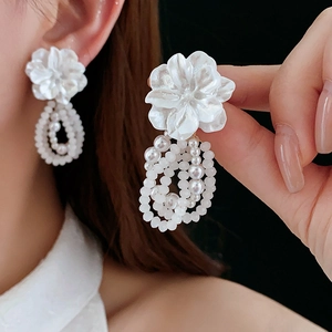 Detail of floral earrings with cascading faux pearl tassels on a model for a vintage look