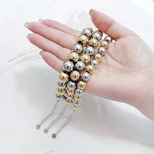 Detail of multi-layer waterproof gold and silver stainless steel bead bracelets held in hand
