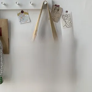 Detail der karierten Canvas-Tasche mit braunen Ledergriffen und Metallnieten