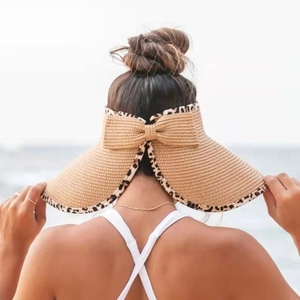 Detail of female straw sun hat with elegant bow and stylish leopard print trim edge