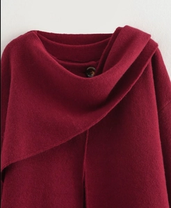 Dettaglio dello scollo di un cardigan in maglia rosso intenso con bottone nero decorativo