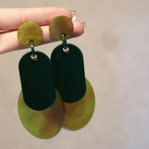 Exaggerated geometric acrylic earrings with green marble texture on a plain background