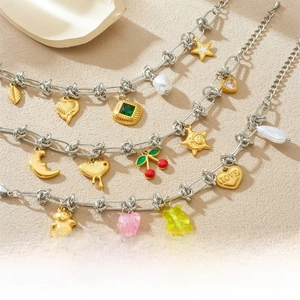 Close-up of golden heart, cherry and bear charms on a chunky silver stainless steel chain