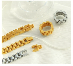 Close-up of gold and silver watchband style chain bracelets and rings on white fabric