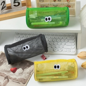 Close-up of mesh pencil bags with cute eye dolls on a desk with keyboard and calendar