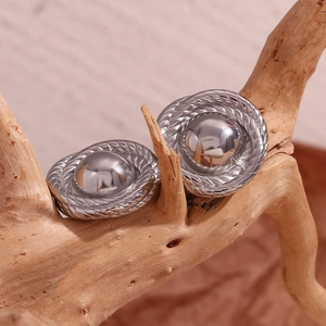 Macro shot of silver twisted metal stud earrings placed on natural weathered wood