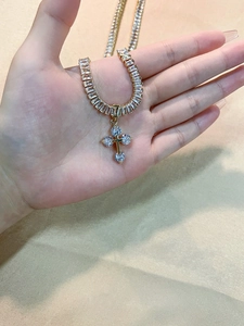 Detail of a luxury gold cross necklace with shimmering zircon stones held in hand