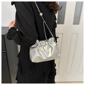 Detail of silver pleated cloud bag with metallic texture and elegant chain strap