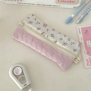 Detail van roze gebloemde patchwork pennenzak met rits op een wit bureau