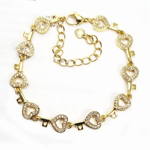 Macro detail of gold-plated heart and key link bracelet with micro-pave cubic zirconia