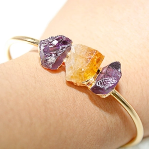 Macro shot of natural amethyst and citrine stones set in a gold-plated adjustable cuff