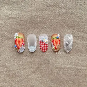 Detail view of 3D embossed strawberry nail stickers with lace and red checkered patterns