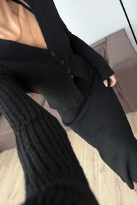Dettaglio del set in maglia nera con cardigan a V e gonna lunga a costine sottili