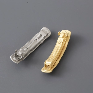 Golden and silver irregular metal spring hair clips with brushed texture on grey background